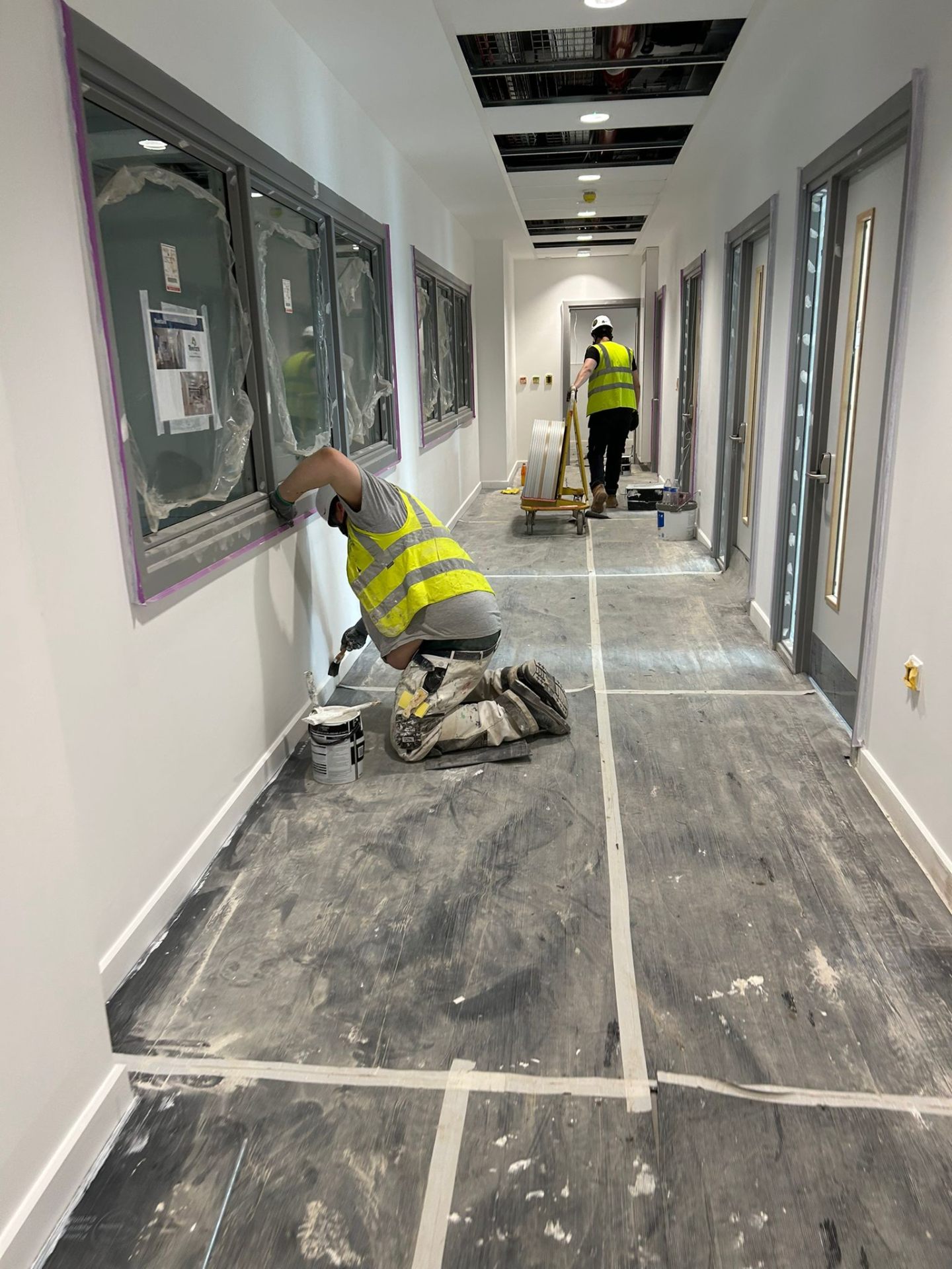 Bendrick decorator caulking skirting boards in a freshly painted clinic corridor