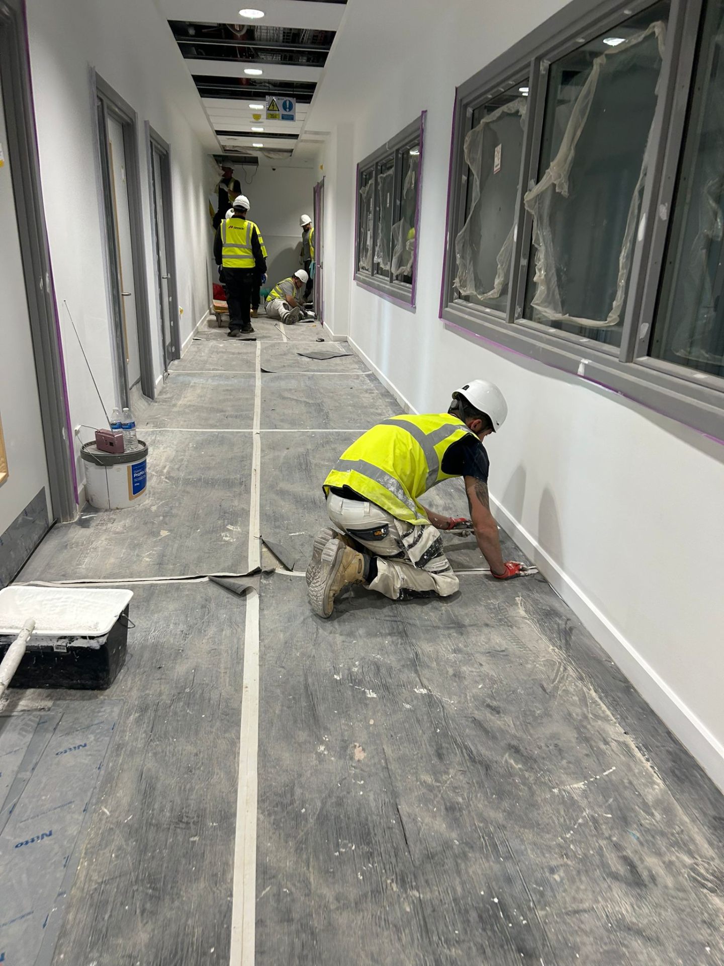 Bendrick decorator caulking skirting boards in a freshly painted clinic corridor