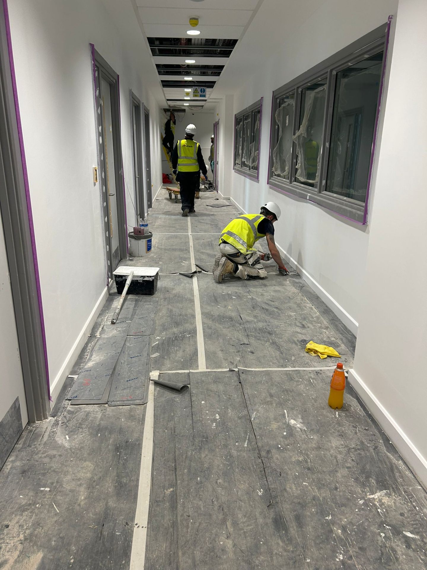 Bendrick decorator caulking skirting boards in a freshly painted clinic corridor