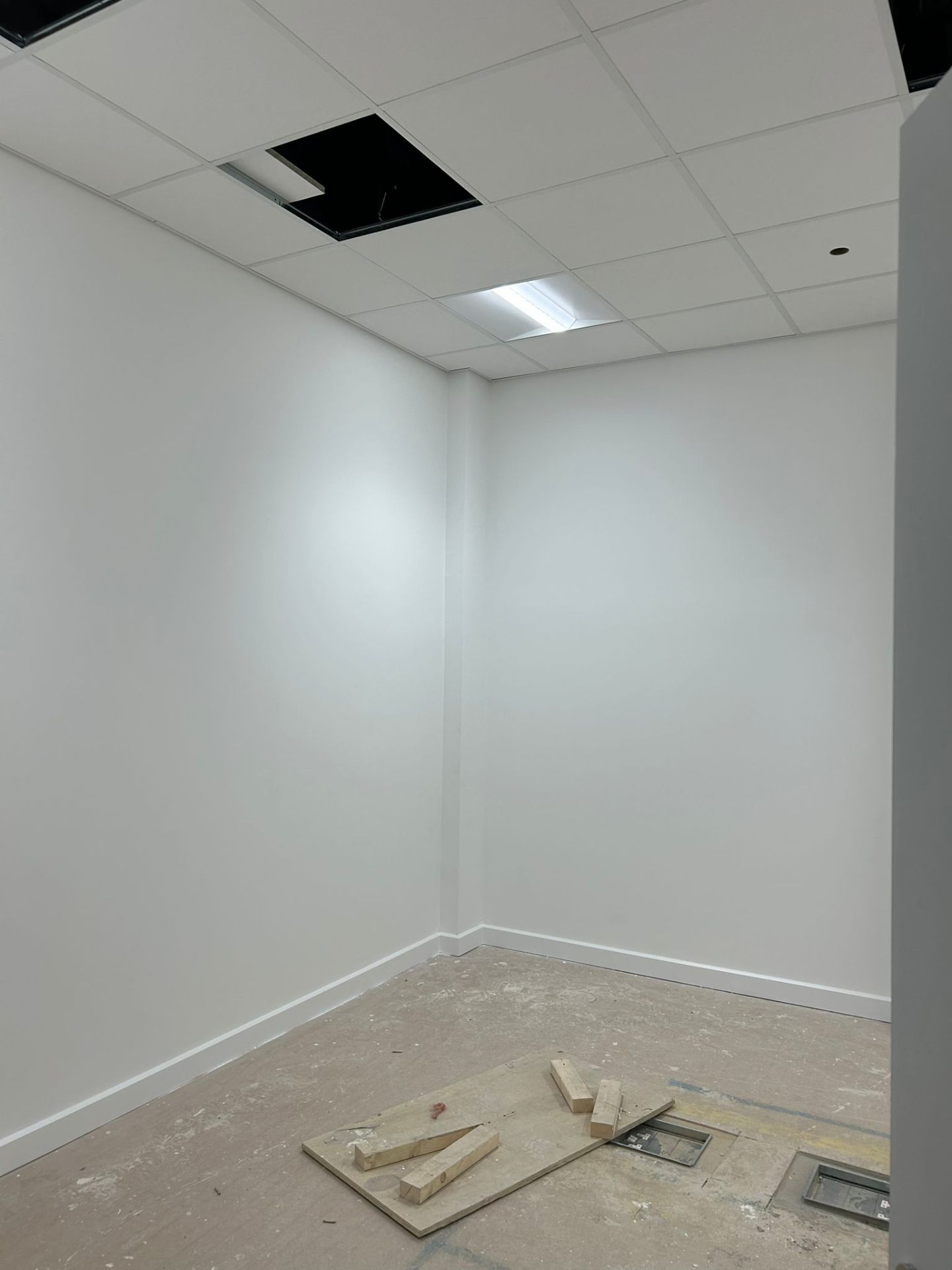 Bendrick decorator caulking skirting boards in a freshly painted clinic corridor