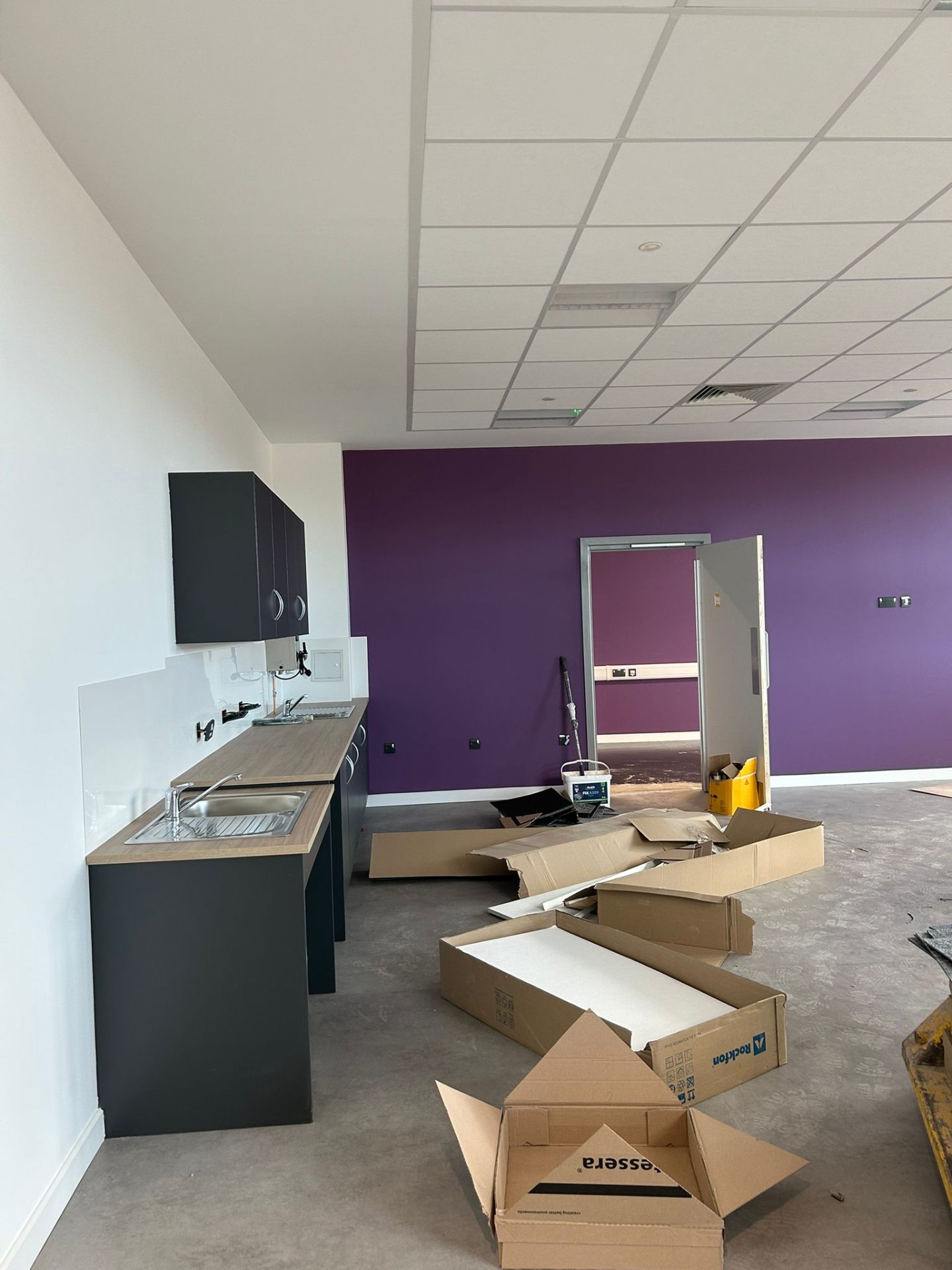 Open-plan office with bold purple feature wall and crisp white finish